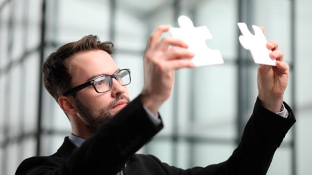 Business puzzle, strategy and marketing. Businessman shows silver pieces of the puzzleの写真素材