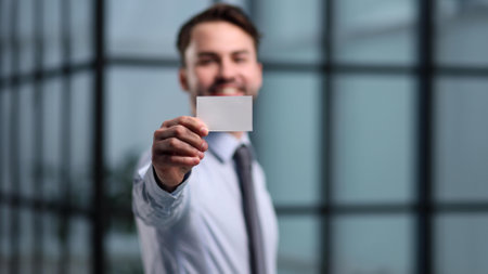 business man holding empty white business card in modern office building. Free blank copy space.の写真素材