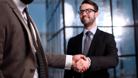 Two businessmen shaking hands and making a deal in an office corridorの写真素材