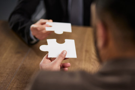 two businessmen put together a puzzle opposite each other close-up