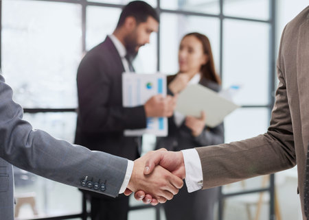close-up of a handshake of business partners against the background of colleaguesの写真素材