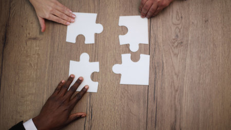 Diverse team people assembling jigsaw puzzle, multiracial group of black and white colleagues engaging in succesの写真素材