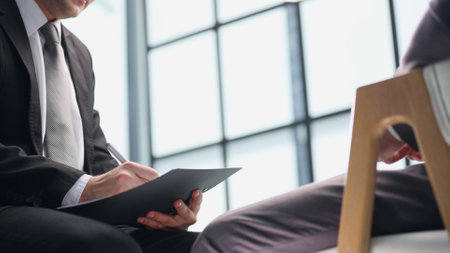 manager holding business documents and a pen while talkingの写真素材