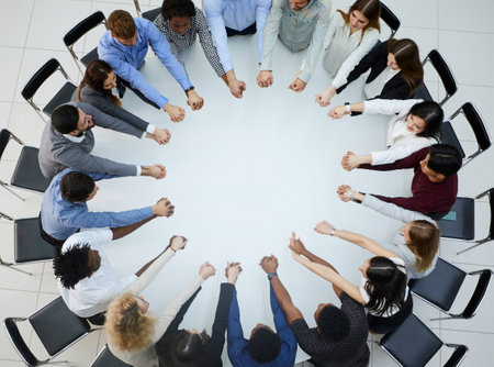 a large group of people sitting at a round table with their arms outstretched