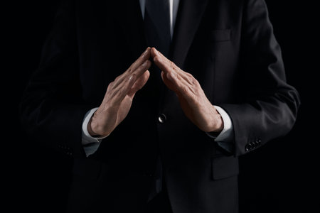 the hands of a man in a suit shows a triangle sign on a black background