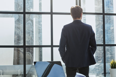 Rear view portrait of a businessman standing in the officeの写真素材