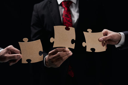 Close-up of business partners putting together three white puzzl