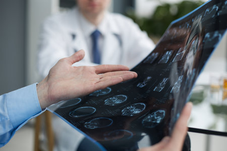 Young man looking at one of x-ray results being shown by his doctor