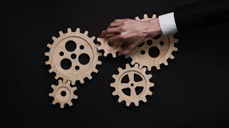 Closeup of a hand holding wooden gears against a black background