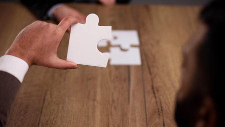 Group of business people putting together a puzzle on a tableの写真素材