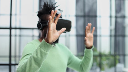 Cool handsome african american man put on virtual reality goggles for the first time in the office.の写真素材