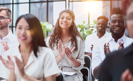 businesswoman applauding during seminar near interracial colleaguesの写真素材