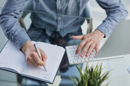 Businessman hand writing note on a notebook close-up. Business man working at office desk.の写真素材