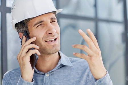 architect in a hard hat speaks on a smartphone.の写真素材