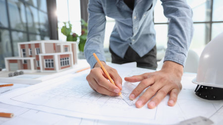 designer drawing graphic design of building project, improvement at table with papersの写真素材