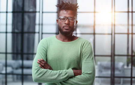 Portrait of a smiling CEO at workplace in a modern office in casual wear with glassesの写真素材