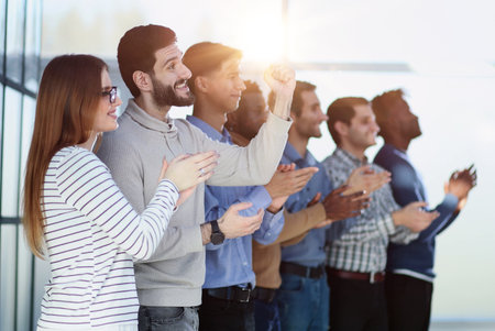A group of people standing in a row clapping their handsの写真素材