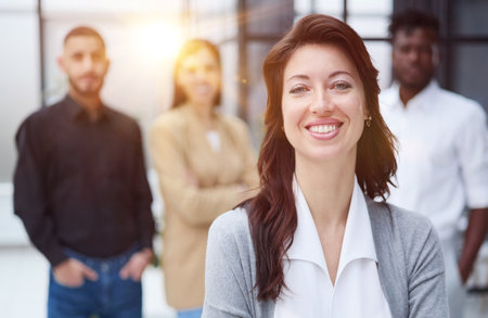 Portrait of a young woman standing in an office with colleagues in the background.の写真素材