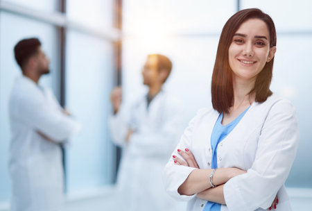 Smiling female doctor in lab coat with arms crossed againstの写真素材