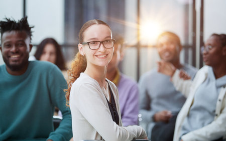 Business woman sitting on a chair with her staff in the background