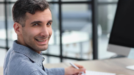 Portrait of young man sitting at his desk in the office