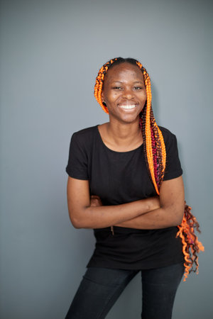 a black woman on a gray background stands holding her hands behind her backの写真素材