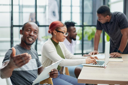 team of employees in a modern office at work. young african american man looking at cameraの写真素材
