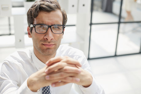 Confident young businessman posing in the office with his hands togetherの写真素材