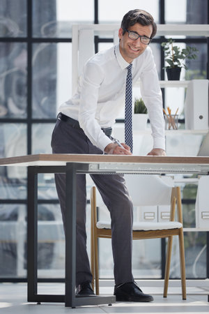 Businessman working in the office standing at the tableの写真素材