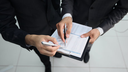 Close-up of business people discussing something while looking at financial reportの写真素材