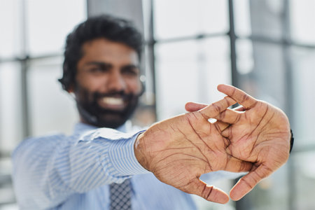 Portrait of a young man with a microphone sitting at his desk in front of a laptop stretches his handsの写真素材