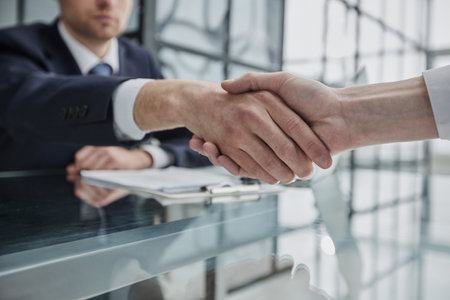 Double up on manpower to make it happen. two businessmen shaking hands during a meeting in a modern office.の写真素材