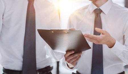 Businesspeople in suits holding a black document folder and pondering about future career opportunities.の写真素材