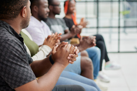 Group of men and women sit in a row and applaud a man who puts forward an idea or says something.
