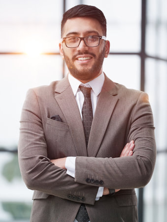 portrait of confident businessman with arms crossed in officeの写真素材