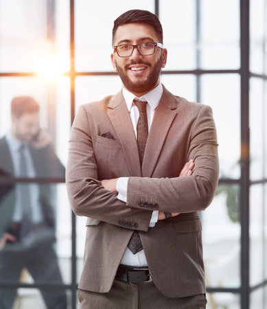 portrait of confident businessman with arms crossed in officeの写真素材