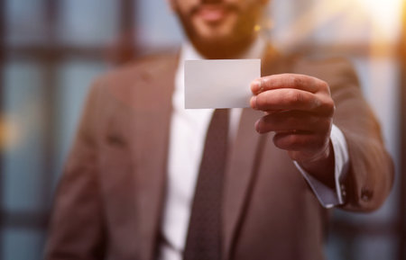 Handsome young man giving business card in modern office