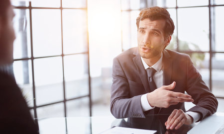 Focused stylish millennial businessman consulting expert, listening to professional advice from boss, coworker, mentor.の写真素材