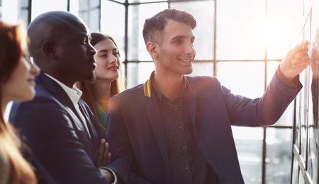 Creative business team looking at sticky notes on glass windowの写真素材