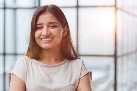 portrait of a smiling business woman with her arms crossed against the backdrop of the officeの写真素材