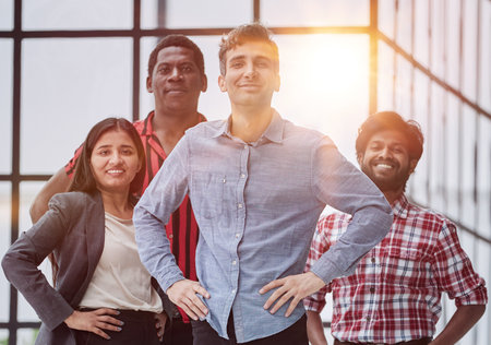 male teamleader standing with crossed arms with coworkers in background