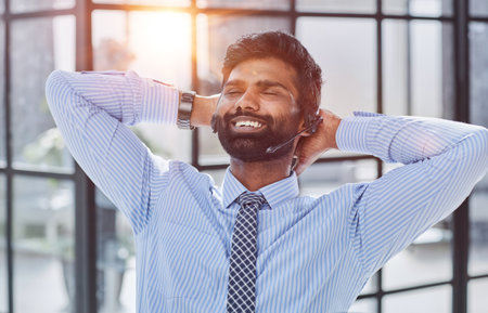 Happy businessman holding hands behind head, relaxing and dreaming about cup of coffee officeの写真素材