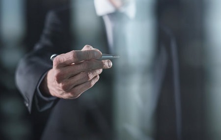 Left hand writing with marker on transparent board on black backgroundの写真素材