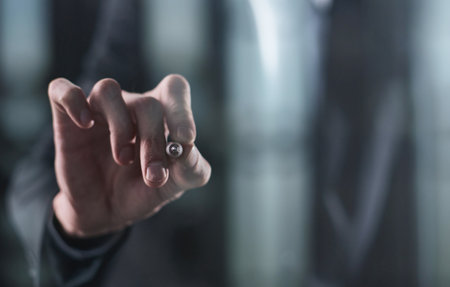 Left hand writing with marker on transparent board on black backgroundの写真素材