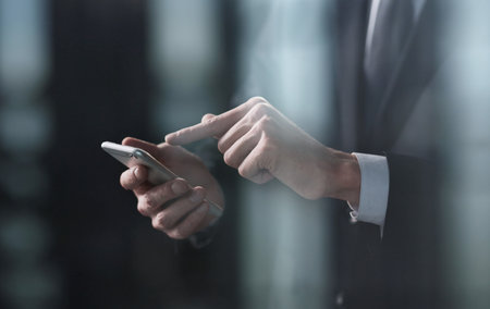 Side view of a mans hand presses a finger on a smartphone. Mock up for your design, copy space.の写真素材