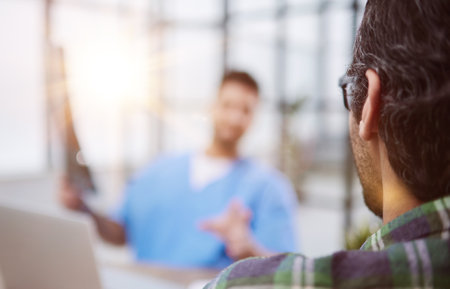 Doctor holding patient x-ray explaining diagnosis in waiting area.の写真素材
