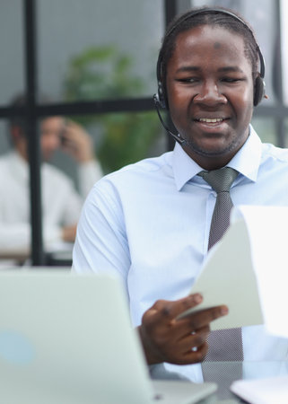 a man at a computer in a call center talking using headphones with a microphoneの写真素材