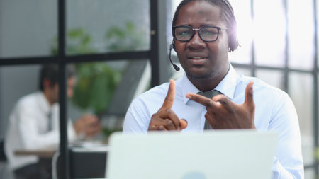 a man at a computer in a call center talking using headphones with a microphoneの写真素材