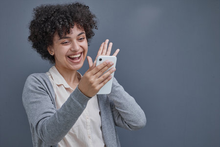 girl on a gray background smiling using the phoneの写真素材