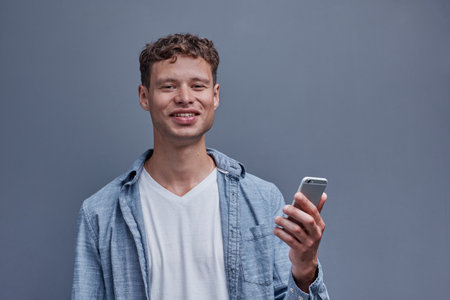 a man on a gray background holds a phone in his handの写真素材